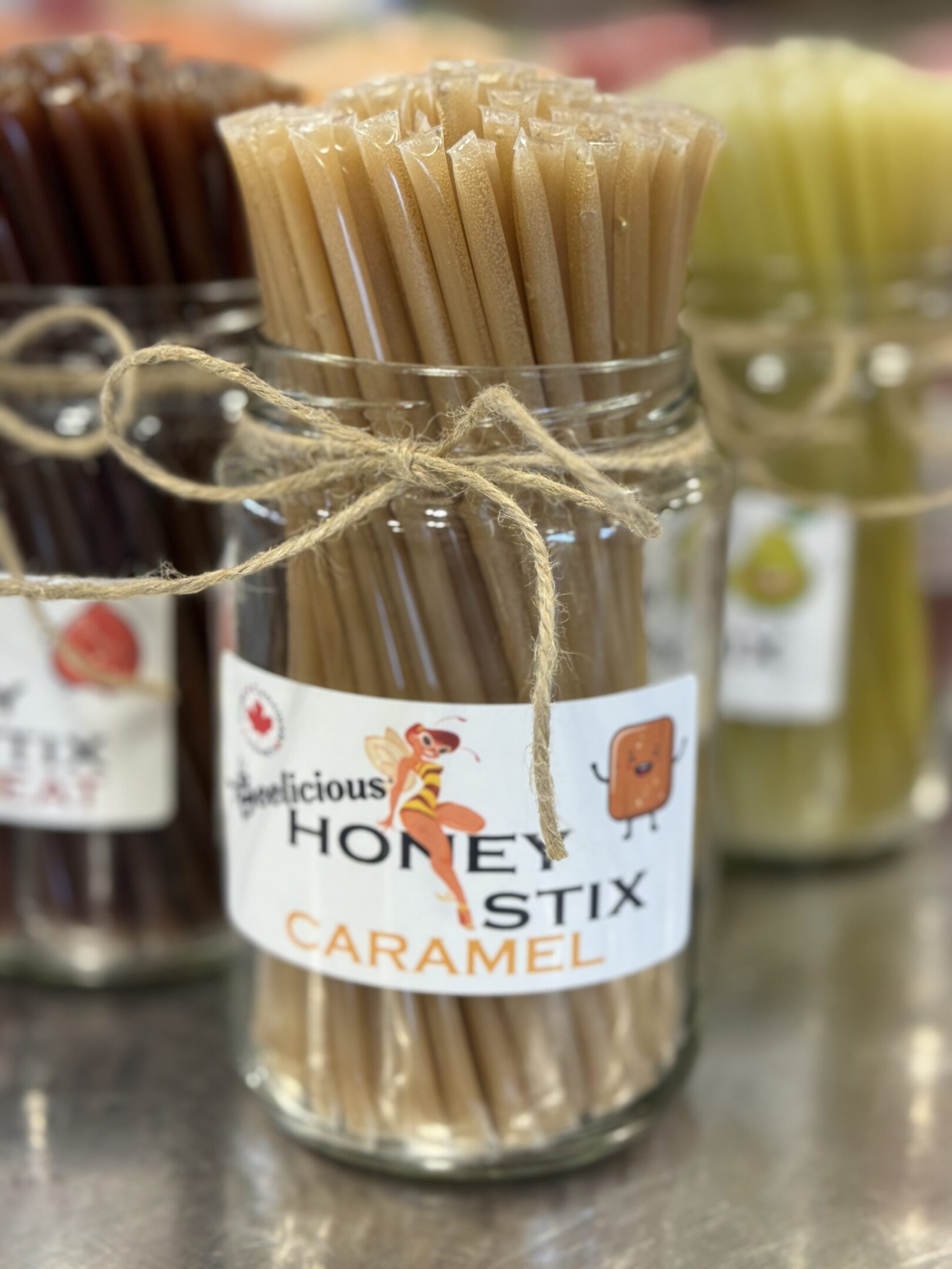 Glass jar with caramel honey teat sticks tied with twine.