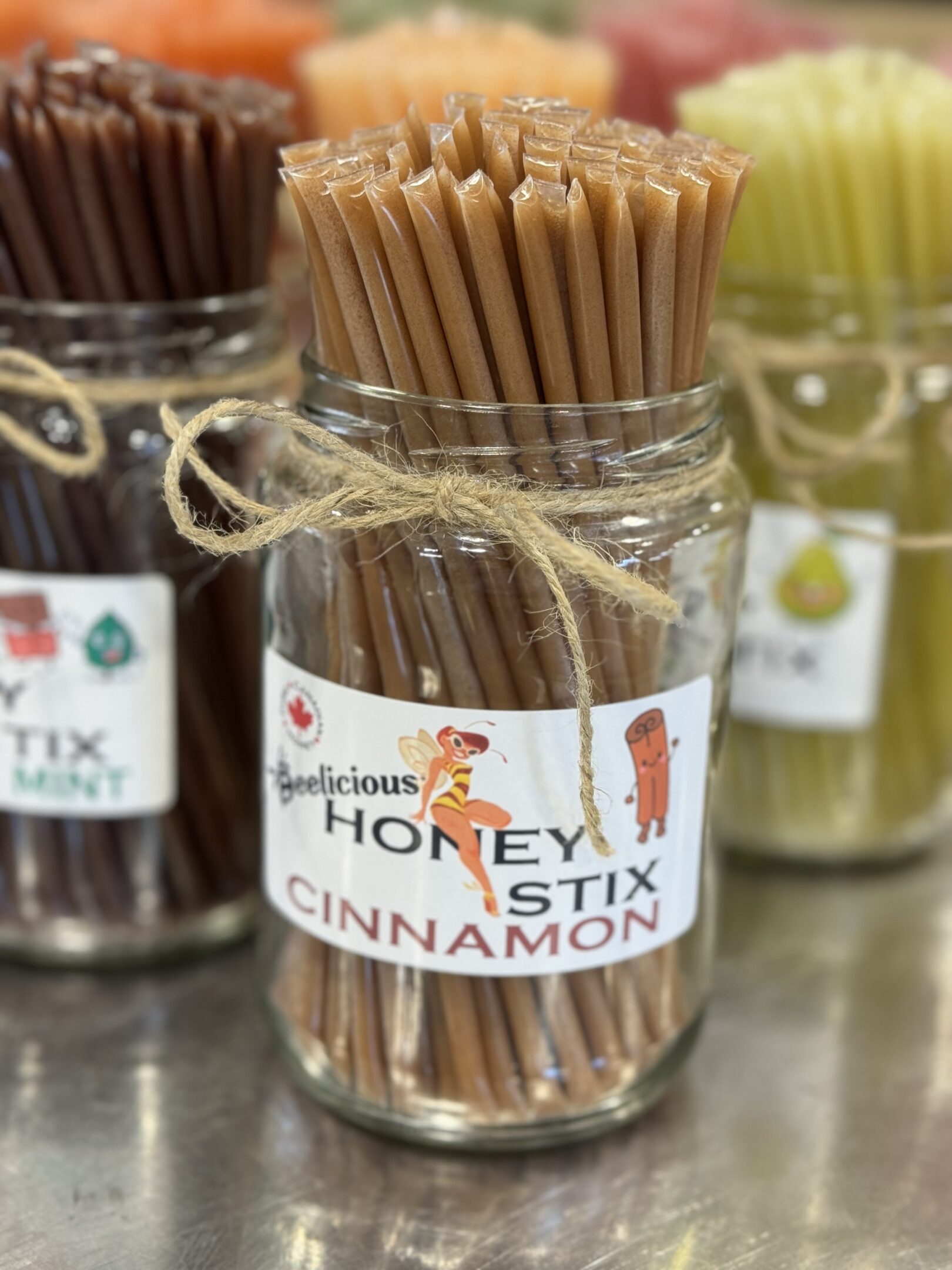 Jar of cinnamon-flavored honey sticks with wooden sticks inside.