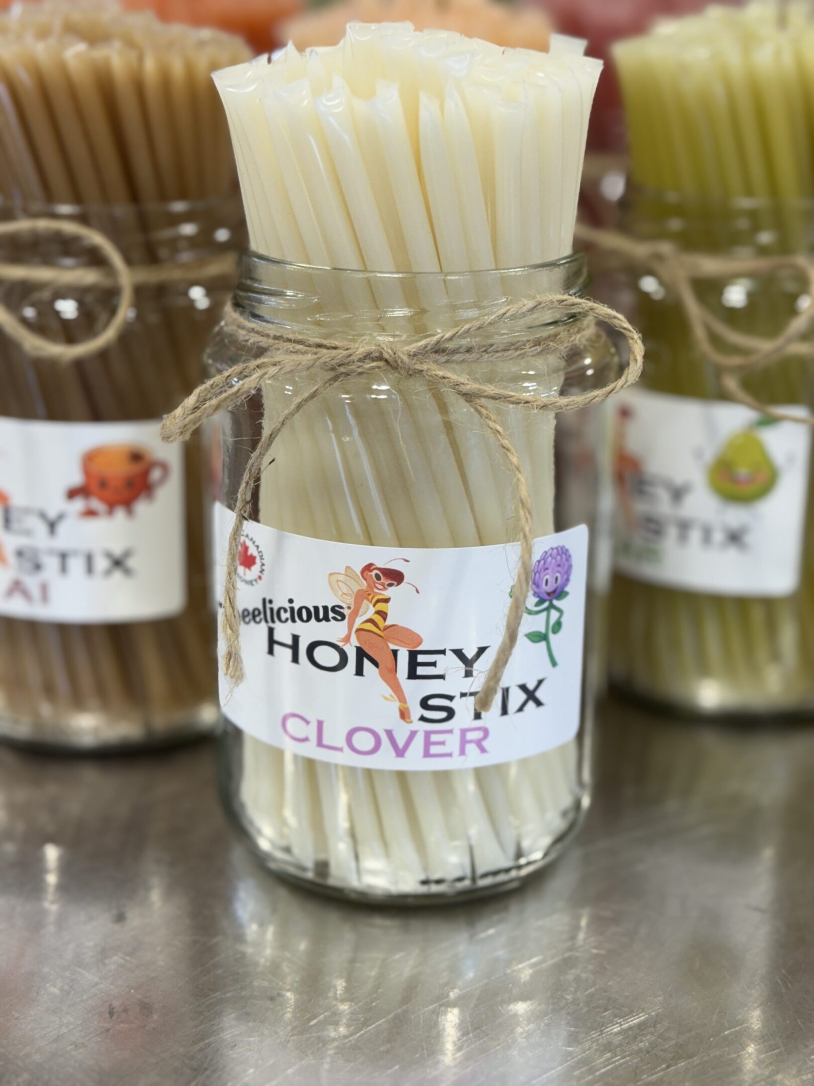 Jar of white clover honey sticks tied with a rustic twine bow.