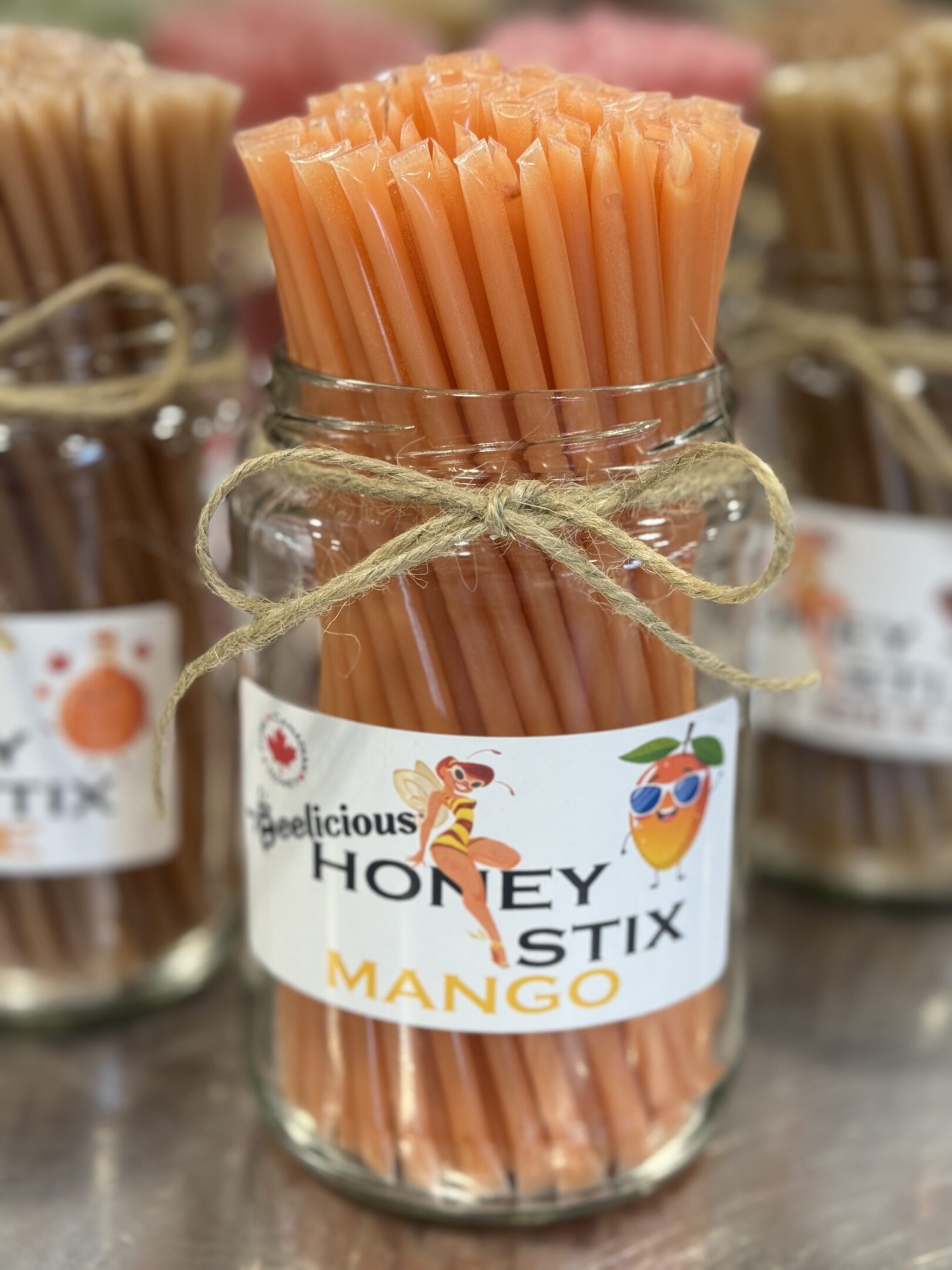 Jar of Honey Stix Mango sticks tied with twine.