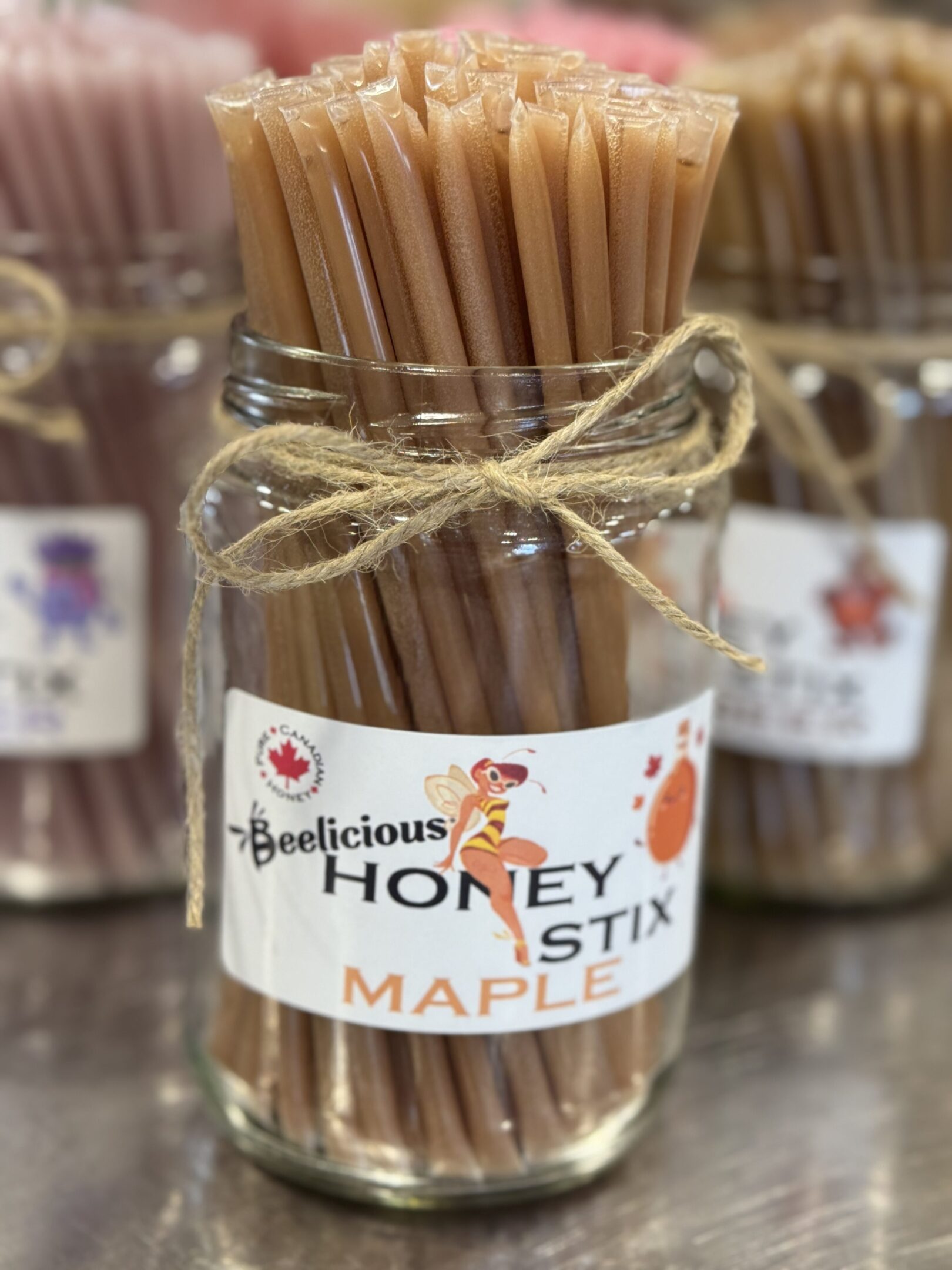 A jar of Beelicious honey maple sticks tied with twine.