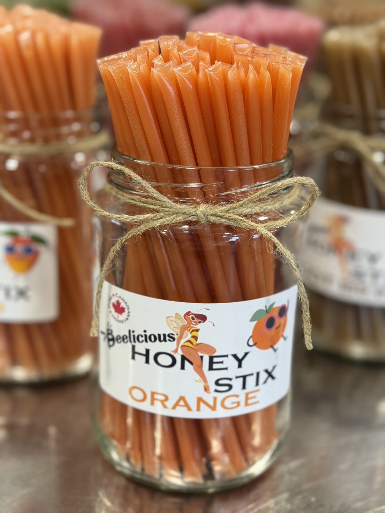 Jar of honey-flavored orange stix with a rustic twine decoration.