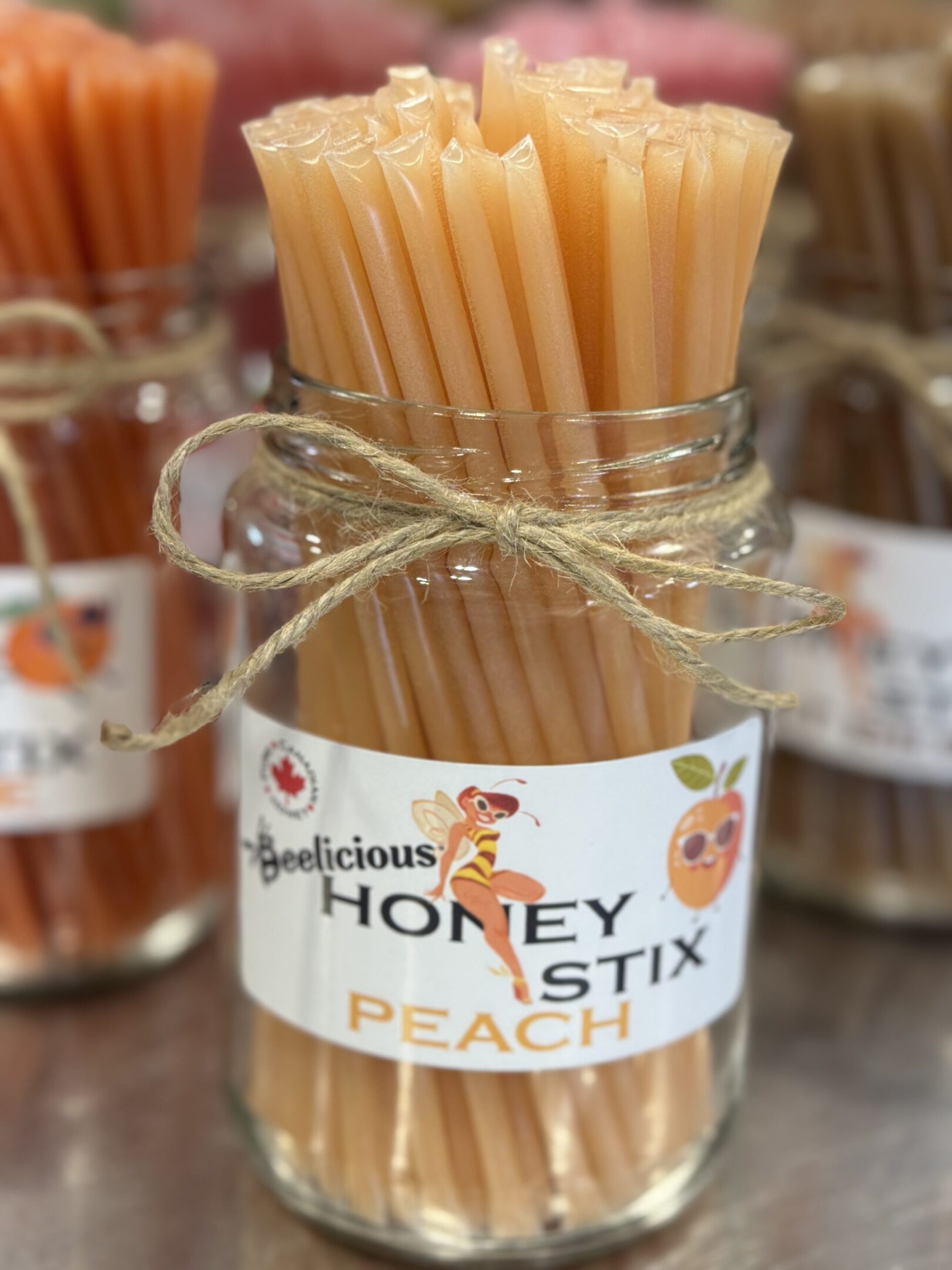 Jar of peach-flavored honey sticks tied with twine.