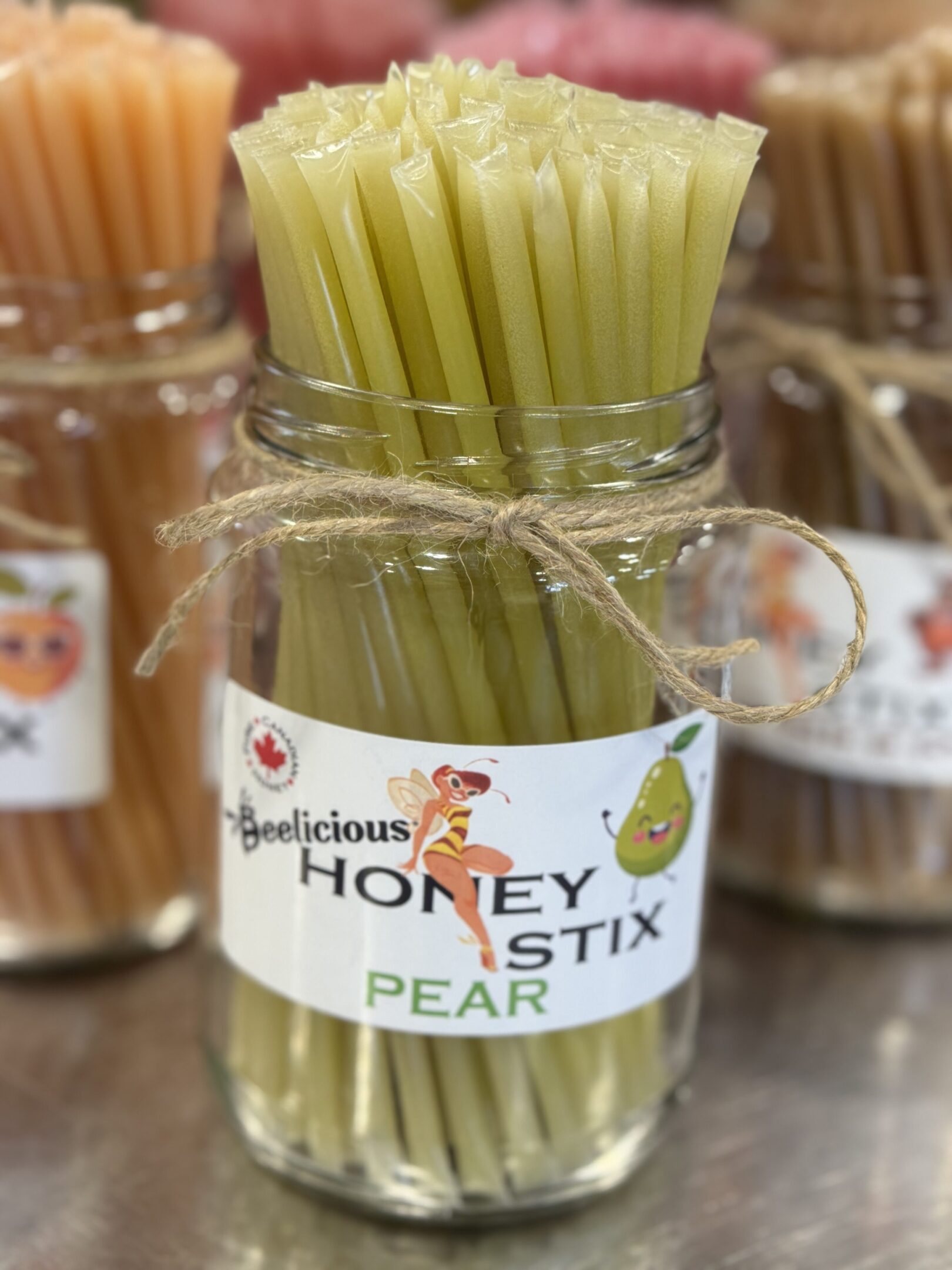 Glass jar with honey pear-flavored sticks tied with twine.