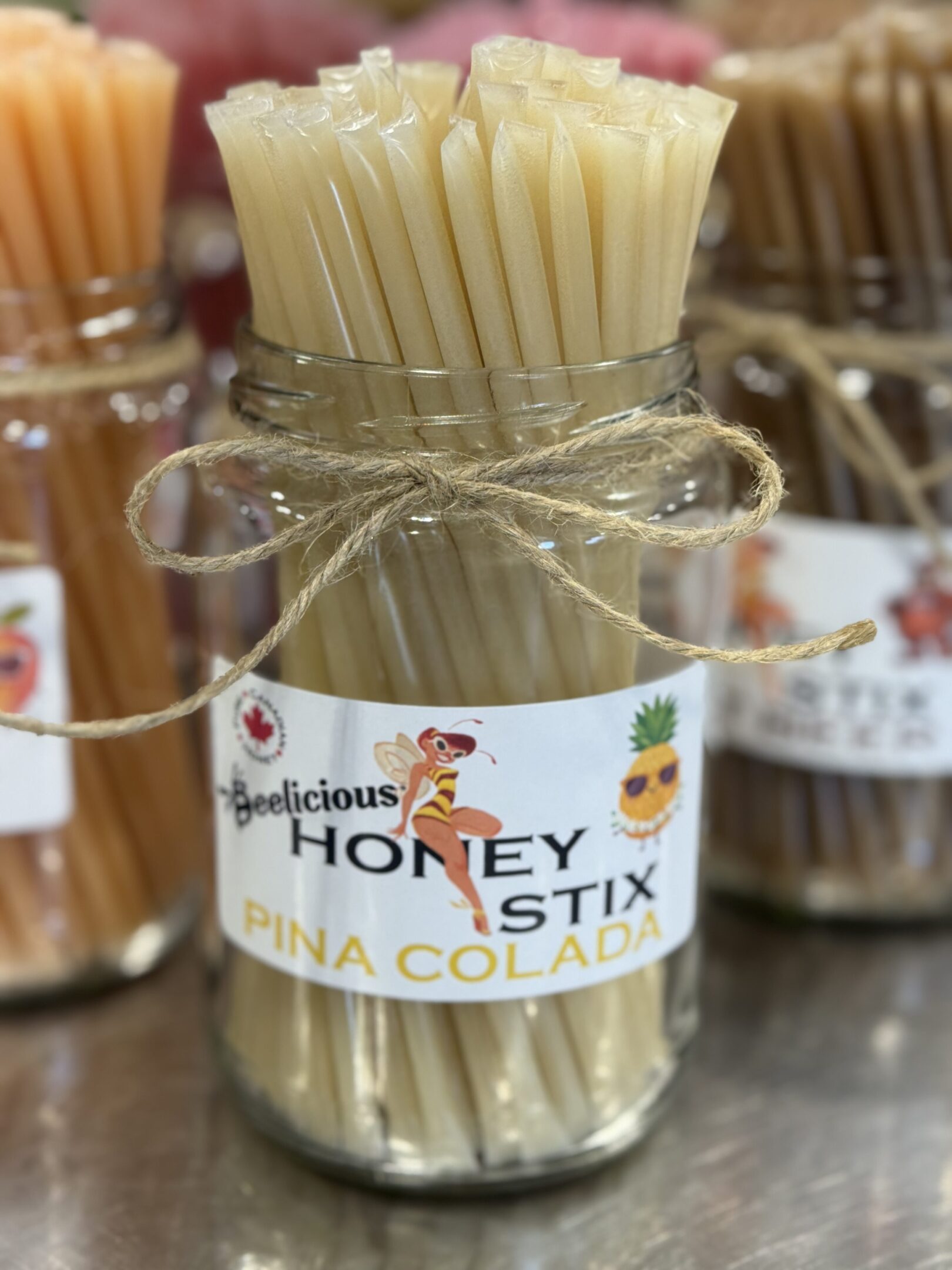 A jar of honey sticks tied with twine and labeled.