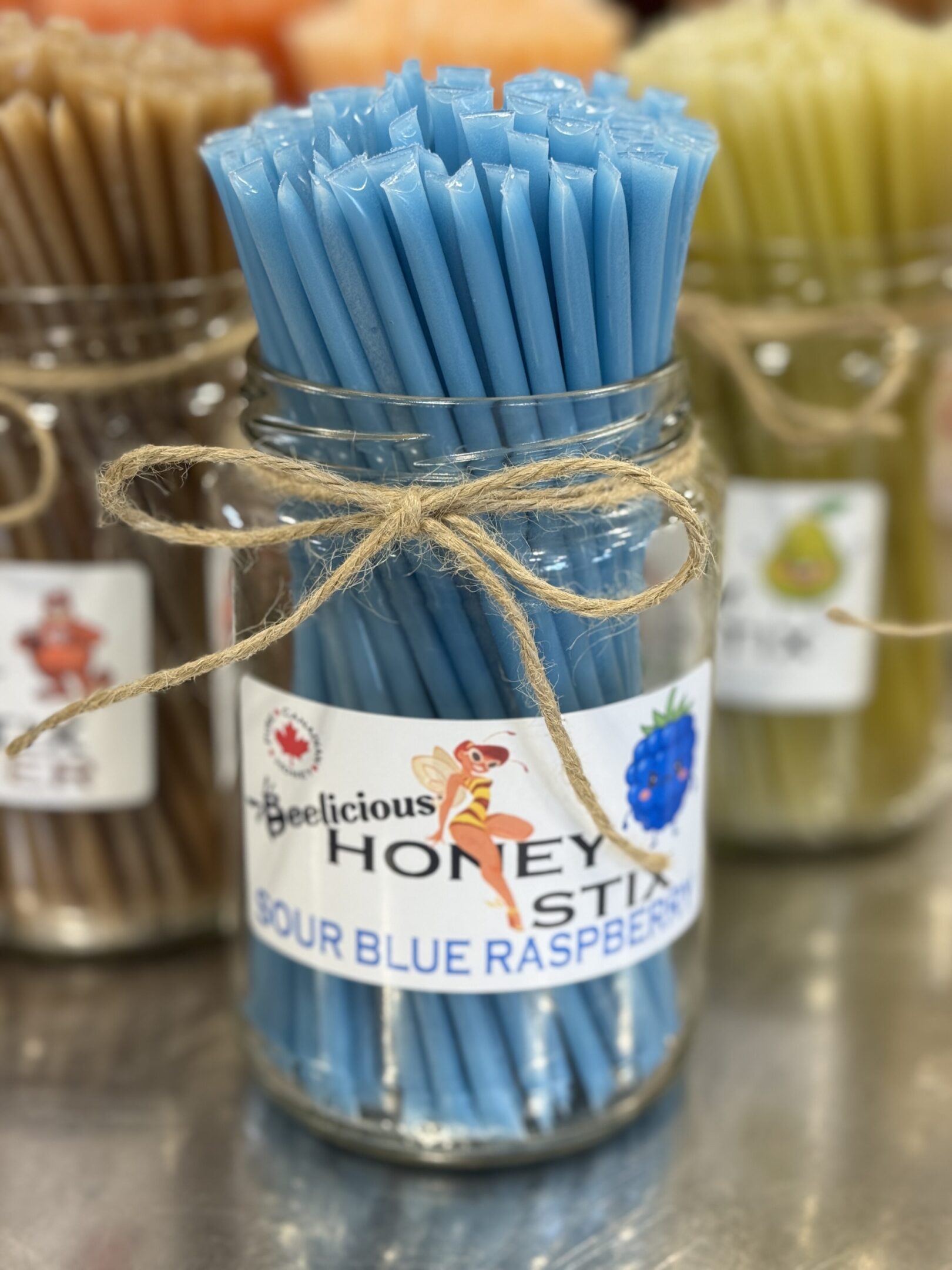 Jar of blue honey dippers labeled for blue raspberry honey.