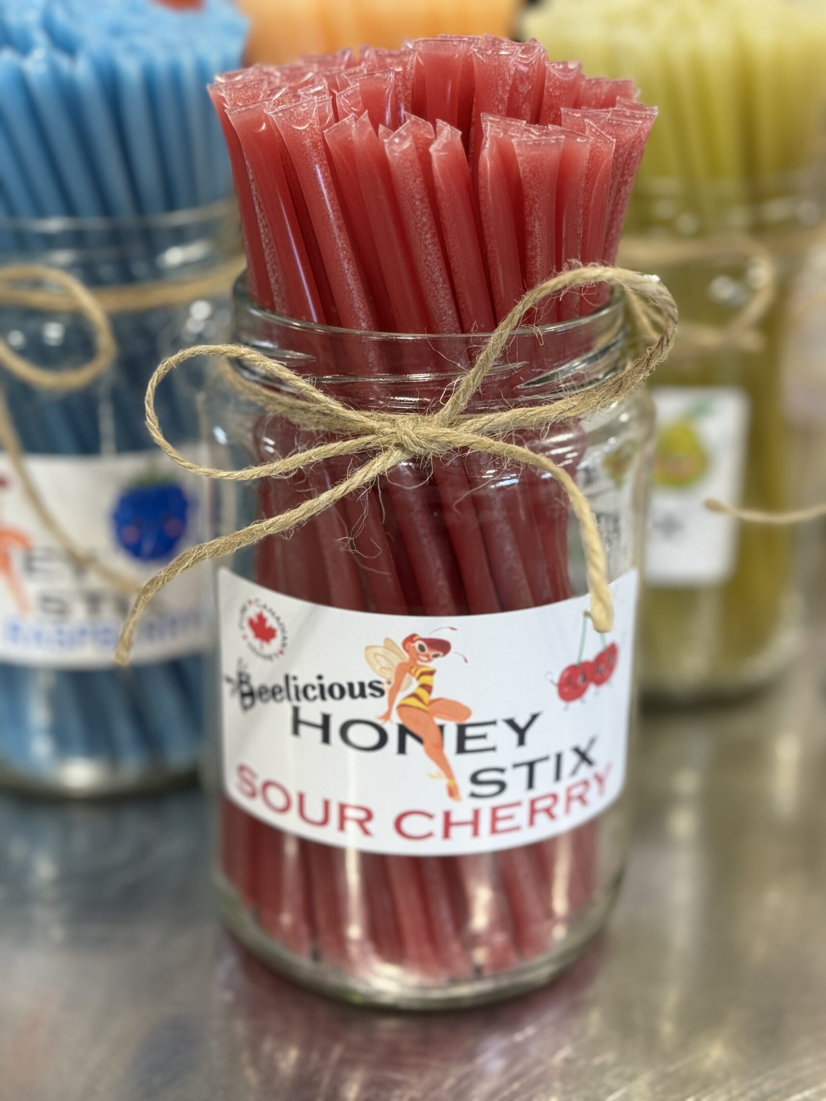 A jar of sour cherry honey stix tied with twine.