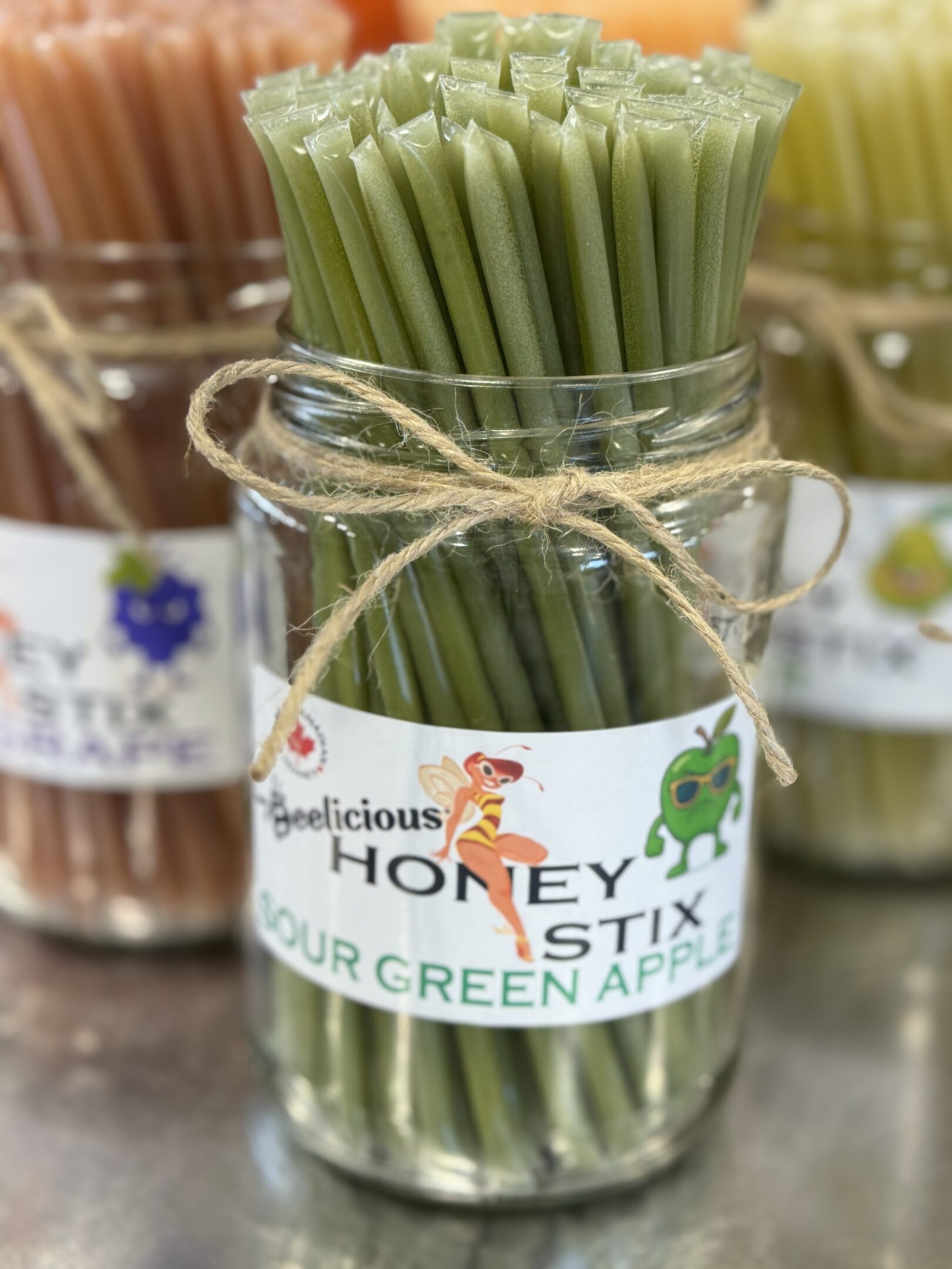 Glass jar with green honey stix tied with twine.